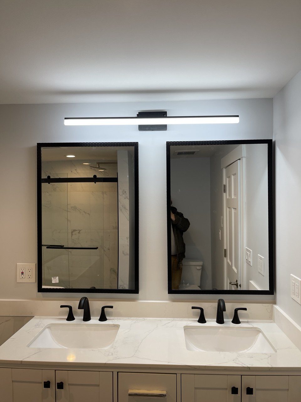 Finished bathroom with a double vanity, quartz top, matte black faucets and black-framed mirrors